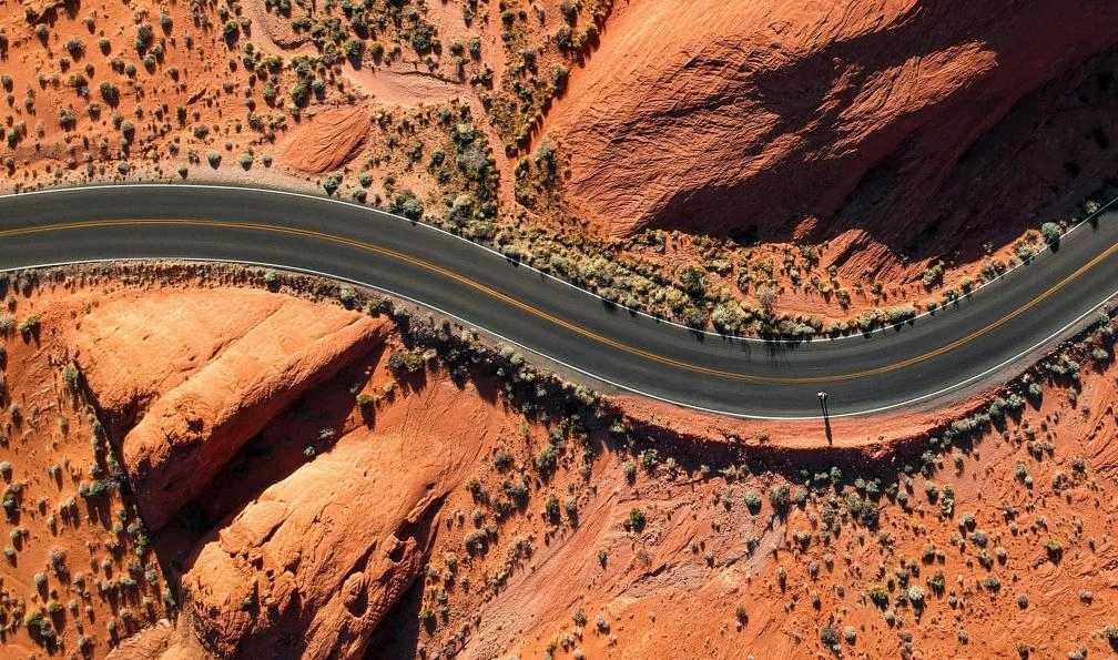 4×4 longeant une route désertique avec dunes à l’horizon.